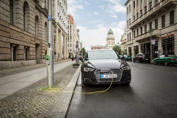 Audi eléctrico recargando en una farola con adaptador Schucko